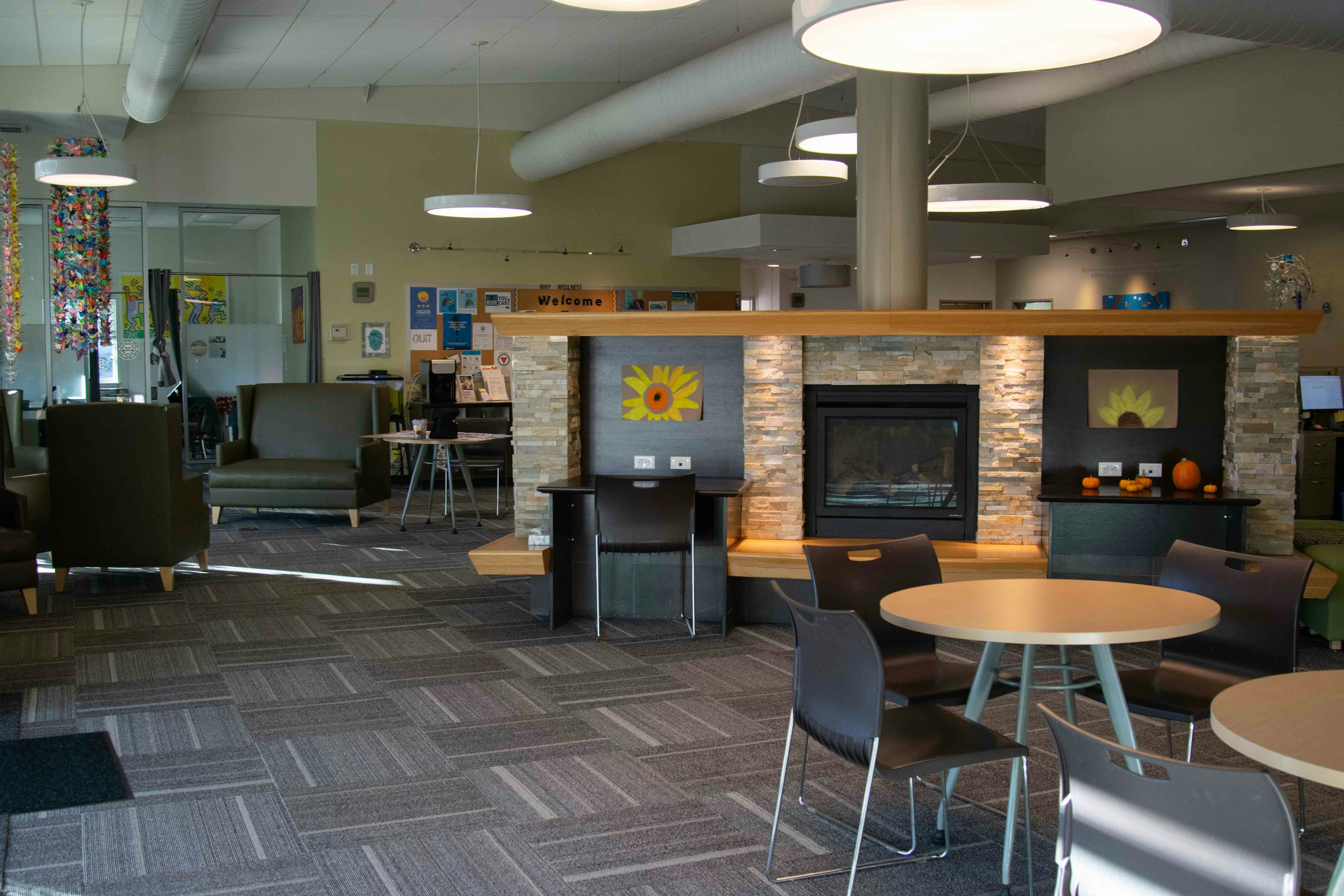 Lobby of wellness center. Tables, chairs, fireplace, and sunflower art work.
