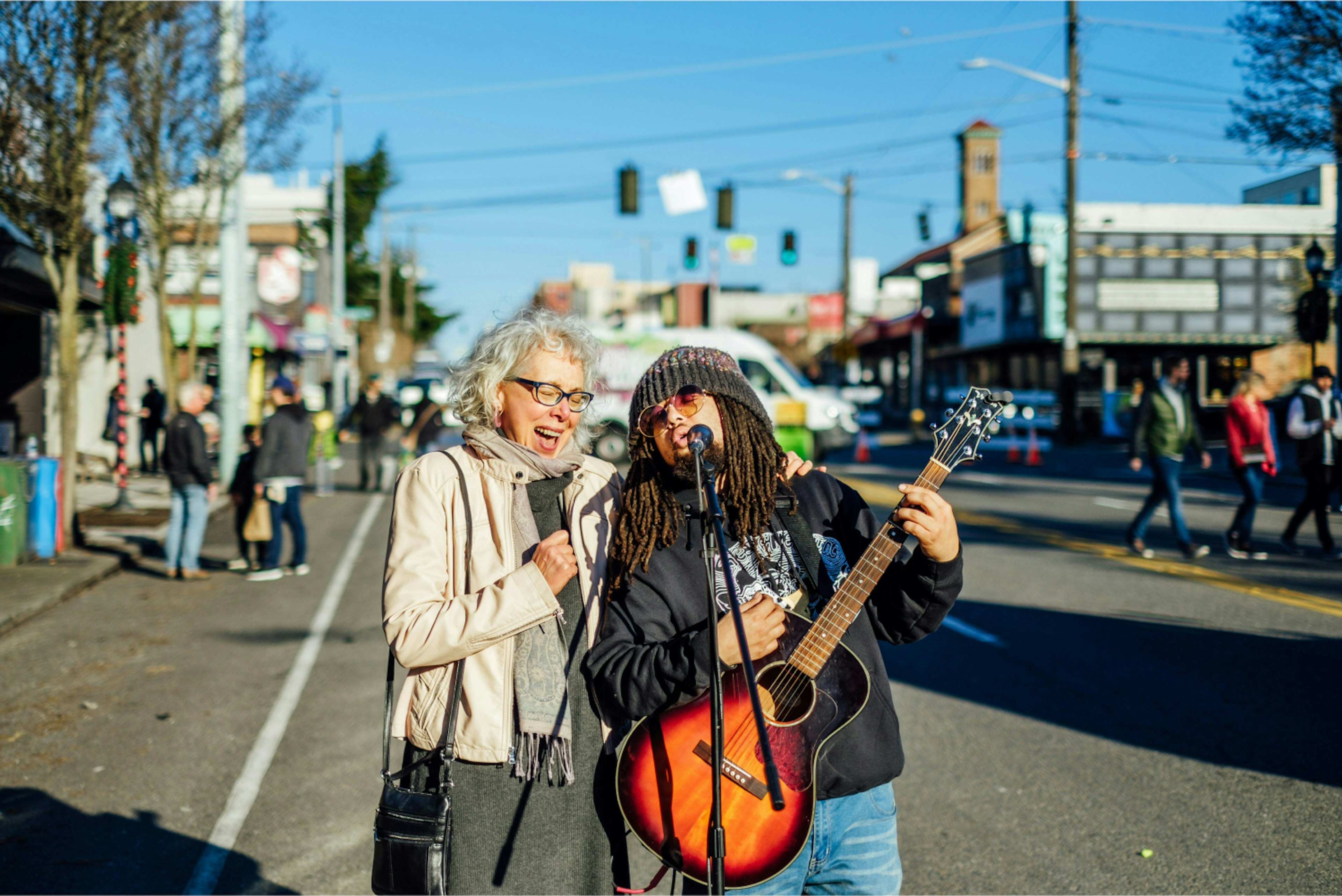 Older woman and younger man playing music and singing in the street.