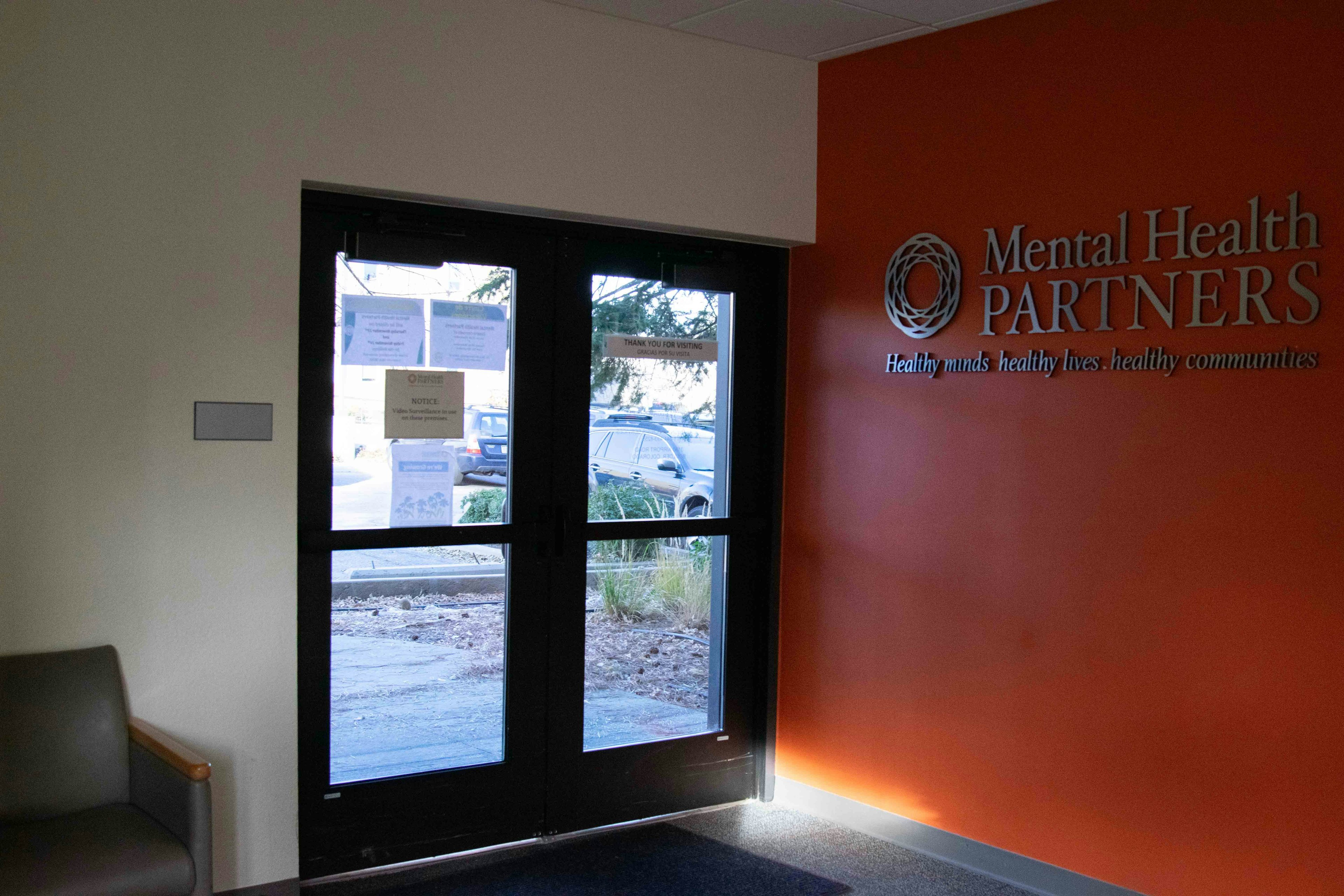 Entry door to Norton building. Glass doors, red wall, and Mental Health Partners logo.
