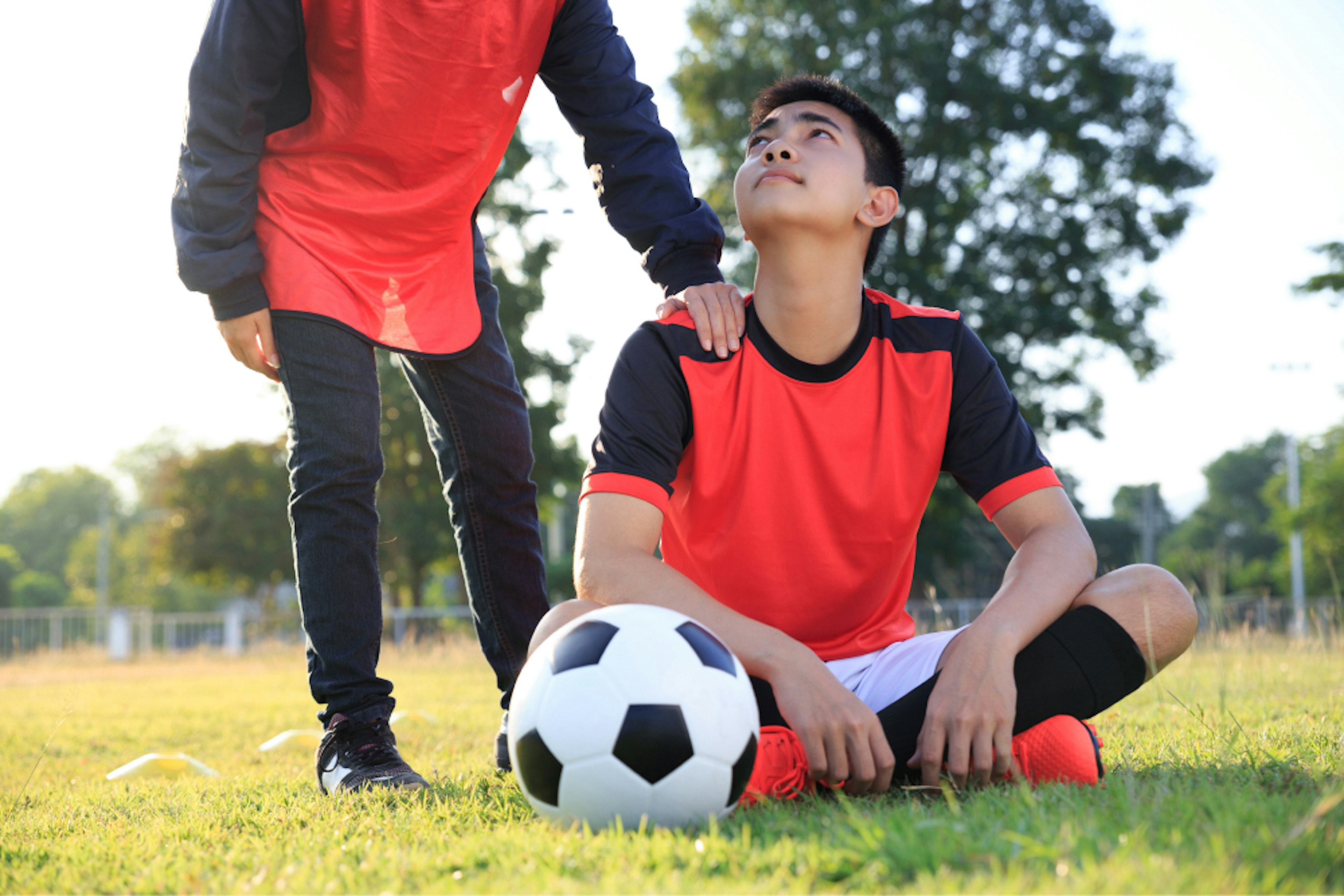 Outpatient Services Tile: teenage sitting on soccer field with soccer ball