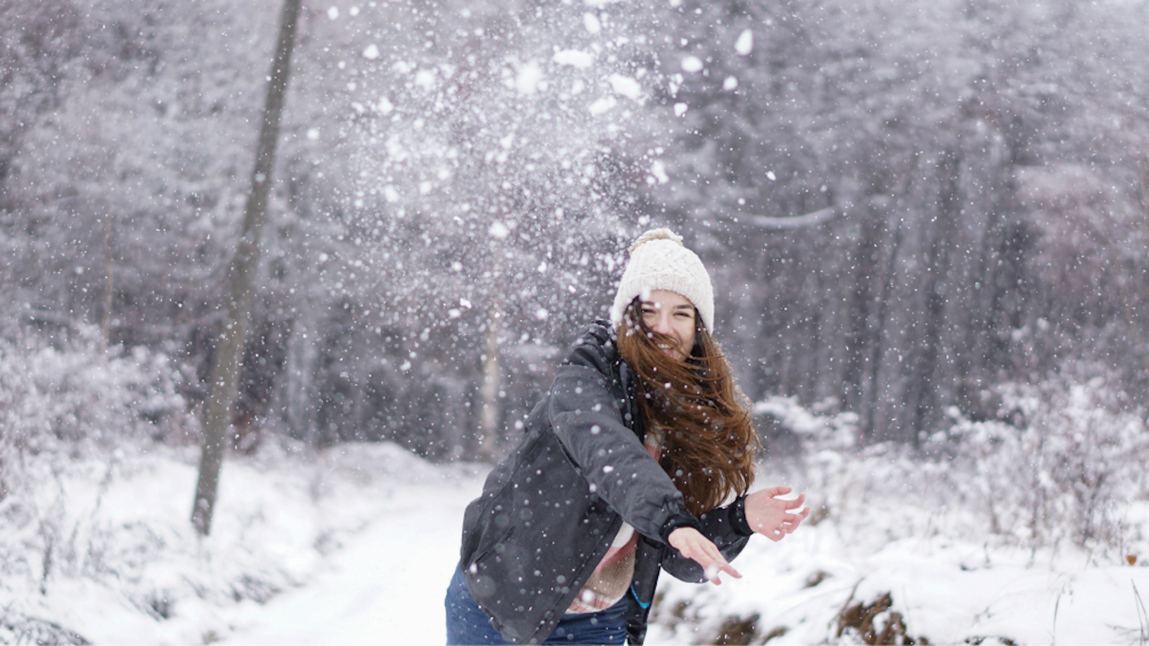 Young woman throwing a snow ball in the woods