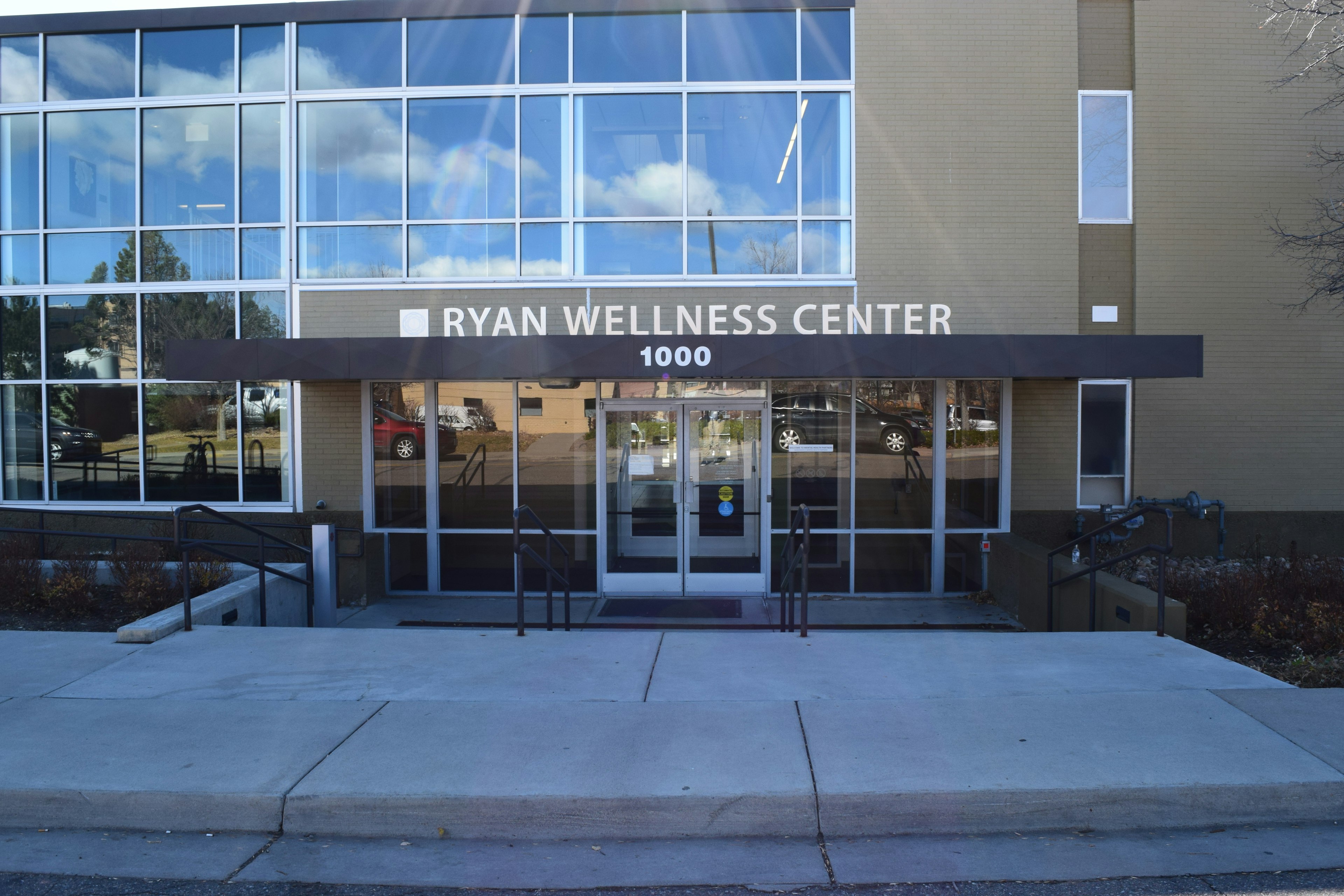 Ryan Wellness Center (rwc) Office Outside. Large wall of windows, tan brick, and lettering that reads "Ryan Wellness Center, 1000"