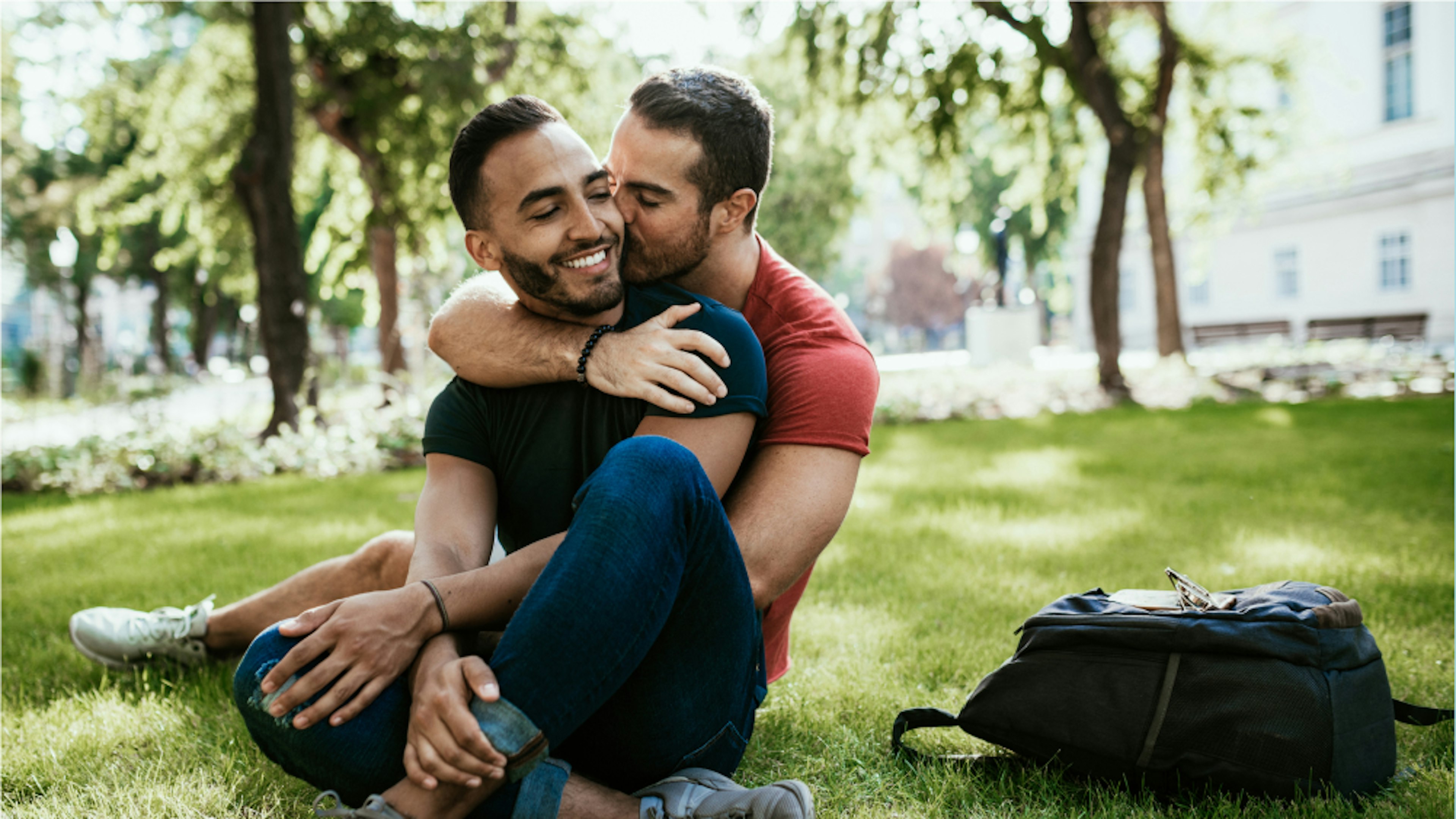 Couple embracing each other while sitting on grass.