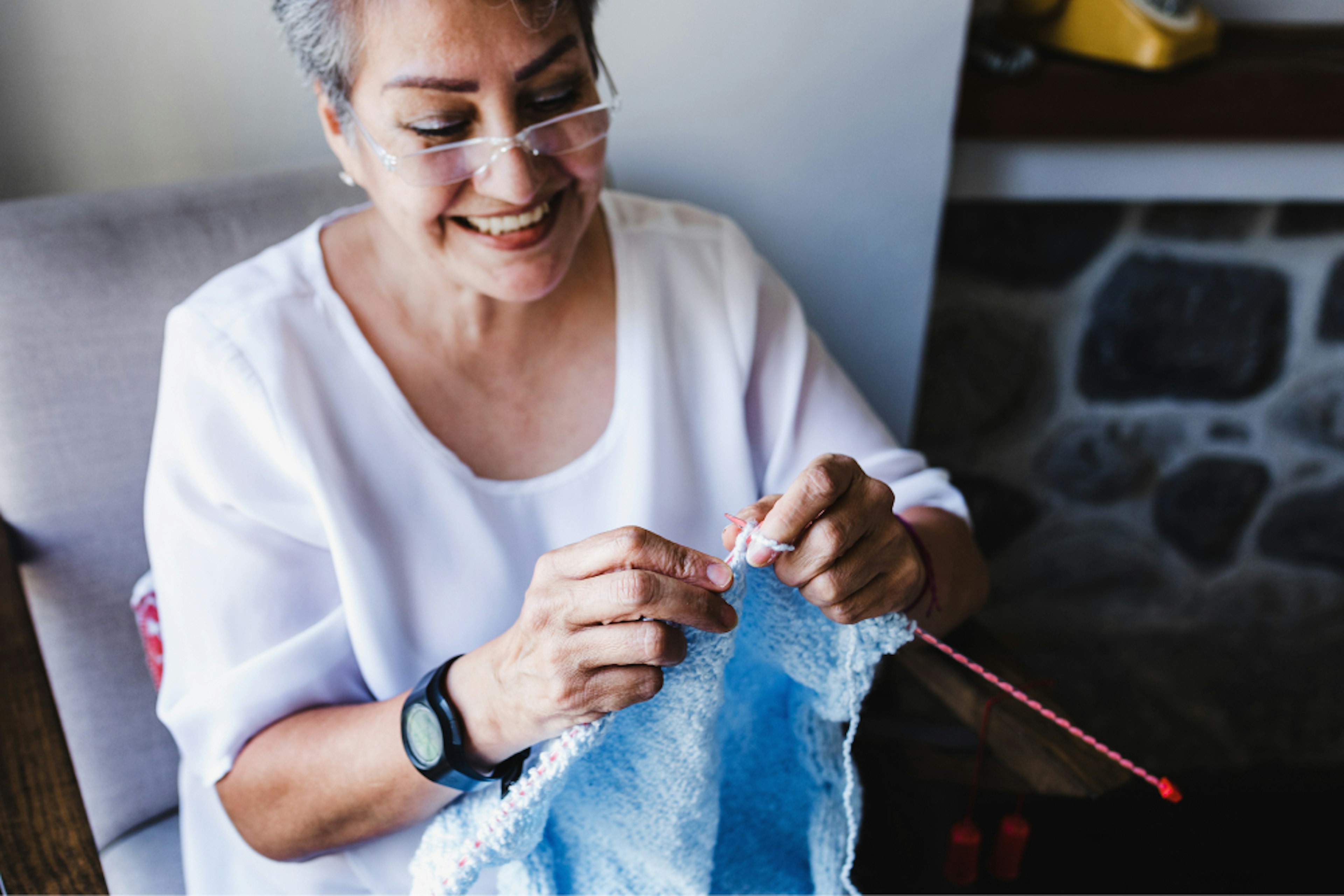 Woman smiling while knitting.