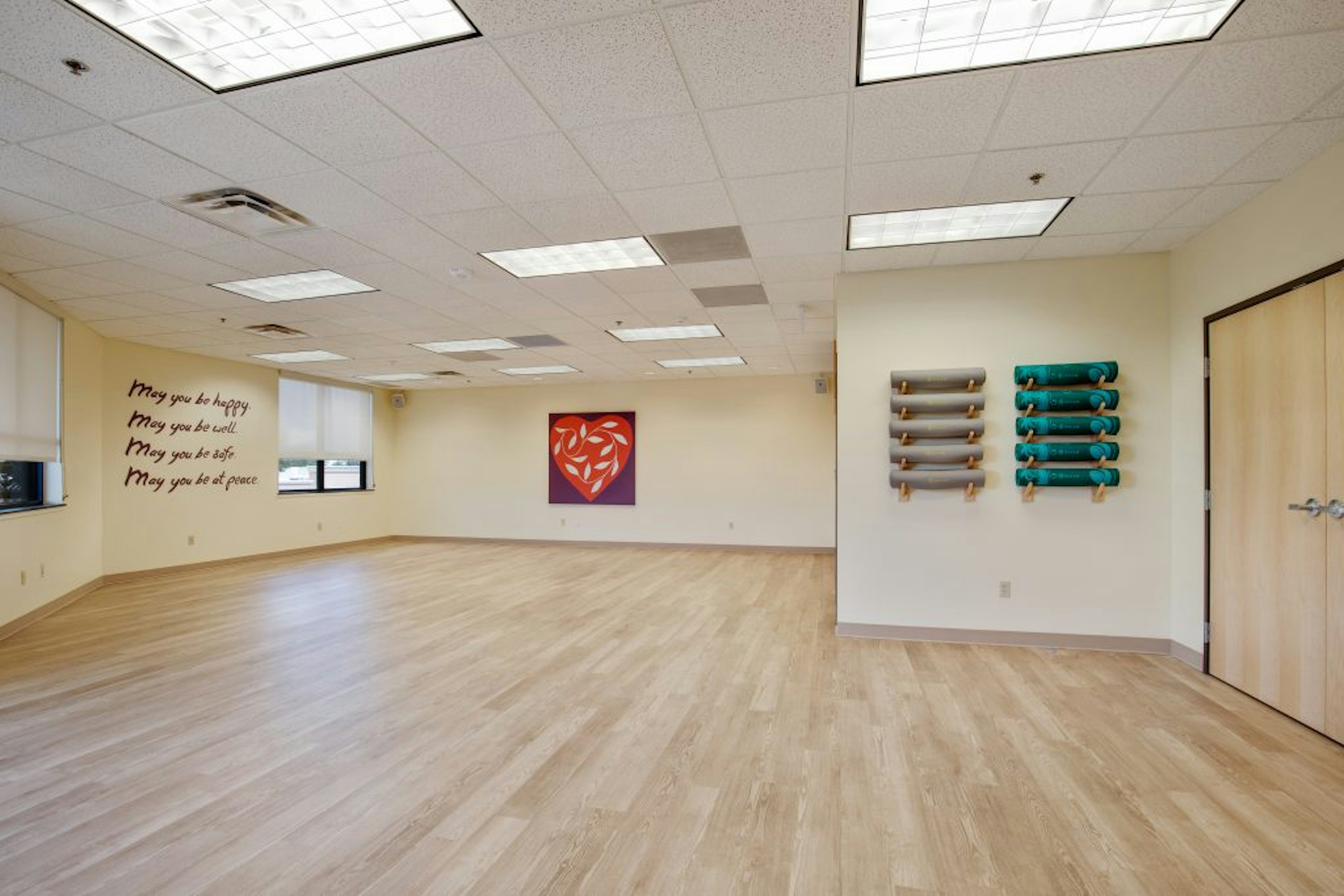 Heart centered yoga studio with mats rolled up against wall.