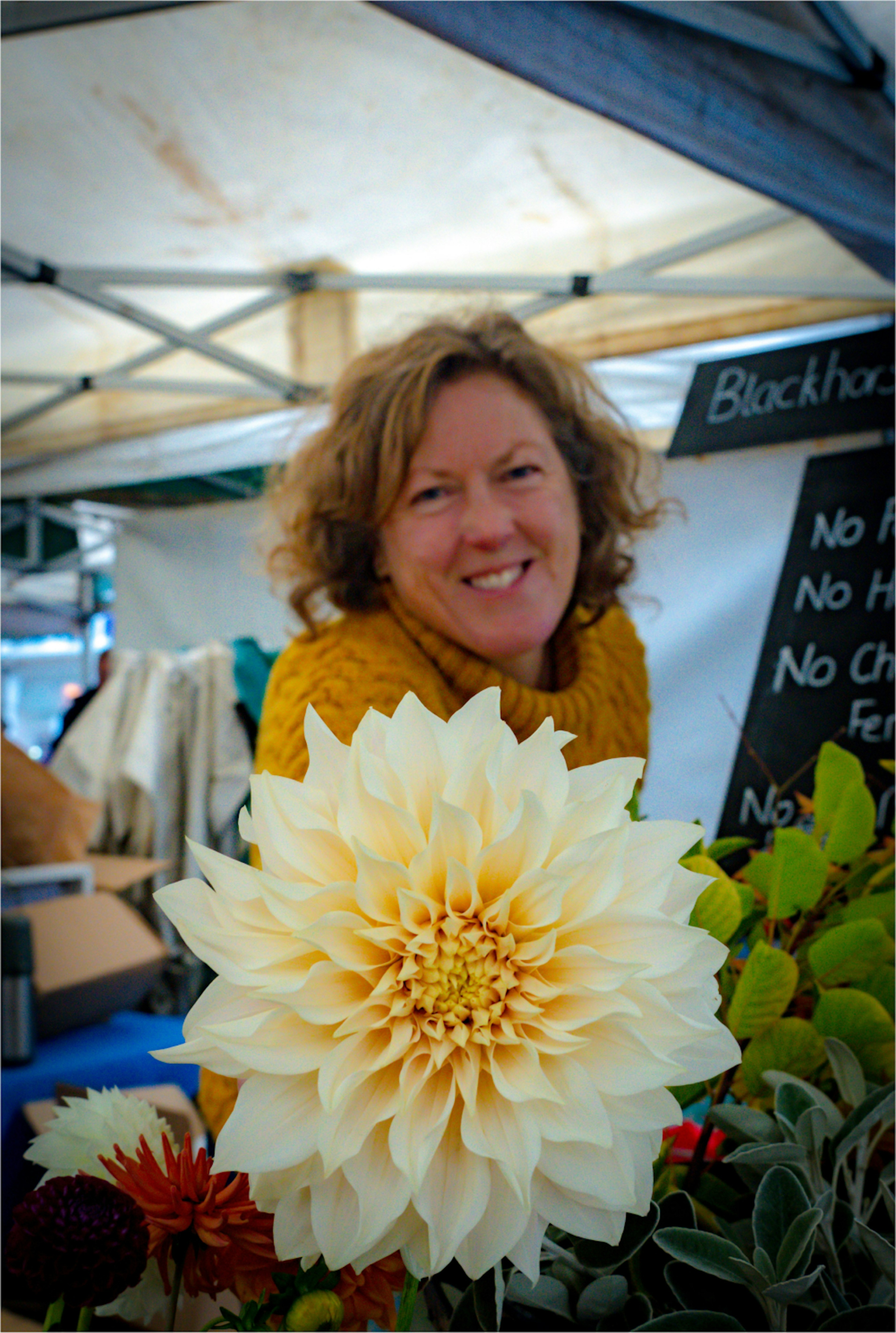 Woman Holding flower while smiling at camera.